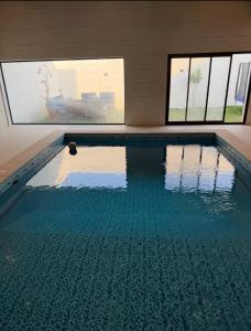 Una piscina con agua azul en una habitación con ventanas. en شاليه داله العماريه 3 بالكامل لك وأجواء ممتعه, en Al ‘Ammārīyah