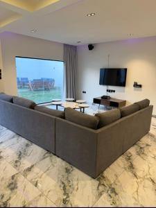Una sala de estar con un sofá grande y un televisor de pantalla plana. en شاليه داله العماريه 3 بالكامل لك وأجواء ممتعه, en Al ‘Ammārīyah