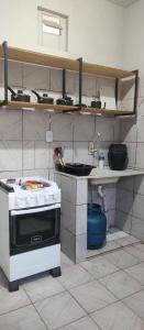 eine Küche mit Herd und Regalen an der Wand in der Unterkunft Sinta-se em casa in Paragominas