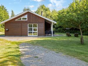 een grote houten hut met een terras en bomen bij Holiday Home Angantir - 4-8km from the sea by Interhome in Byrum