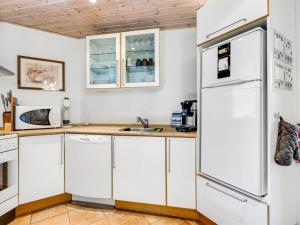 een keuken met witte kasten en een koelkast bij Holiday Home Angantir - 4-8km from the sea by Interhome in Byrum