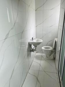 a white bathroom with a toilet and a sink at Sunset in Durban