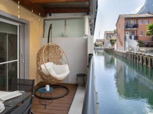 a wicker chair sitting on a balcony next to a river at Apartment Residenz Marina-63 by Interhome in Bouveret