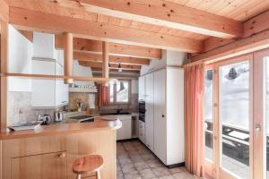 une cuisine avec des armoires blanches et un plafond en bois dans l'établissement Chalet Mouettes, à Riddes