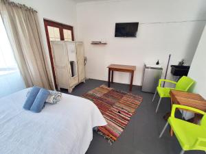 a bedroom with a bed and a table and a television at Bokkomblommetjie in Lambertʼs Bay