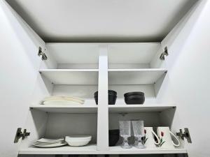 a white shelf with plates and dishes in a kitchen at 윤 작가의 숙소 in Seoul