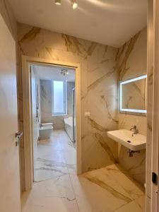 a bathroom with marble walls and a sink and a tub at Hermoso Housing Tortona in Tortona