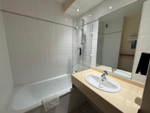 a bathroom with a sink and a tub and a mirror at Kyriad Rennes Sud - Cesson Chantepie in Chantepie +32 photos