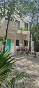une maison blanche avec des arbres devant dans l'établissement Casabel Tulum jungle experience, à Cobá