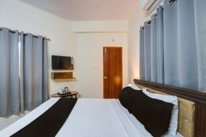 a bedroom with a bed with blue curtains and a television at Super Collection O Sri Nirvana Edge in Hyderabad +23 photos
