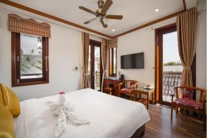 a bedroom with a white bed with a ceiling fan at Villa Ban Hien in Hiếu Nhơn