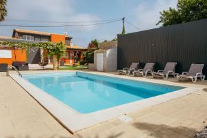 a swimming pool with lounge chairs next to a house at Verde Verdilhão Villa in Arazede