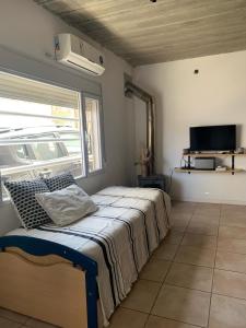 Un dormitorio con una cama en una habitación con ventana. en Casa Monte hermoso a media cuadra Del Mar, en Monte Hermoso