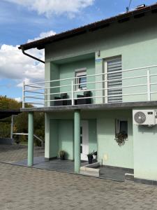 een groen gebouw met een balkon erboven bij Sobe kod bolnice Paprikovac in Banja Luka