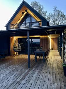 a house with a wooden deck with a table on it at Stodoła Na Kresach - widokowy domek drewniany, całoroczny JACUZZI & SAUNA in Bodzentyn