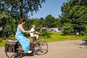 una mujer con vestido montando en bicicleta con un niño en Resort Veldhoven, en Veldhoven