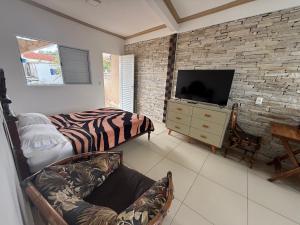 a living room with a tv and a brick wall at Pousada Bela Flor in São Thomé das Letras