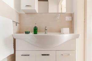 un lavandino bianco del bagno con una bottiglia verde di Casa Angela Apartments a Bergamo Altre 52 foto