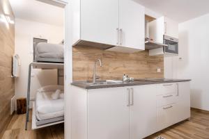 a kitchen with white cabinets and a sink and a bed at Hostdomus - Valle Studio in Grange Sises