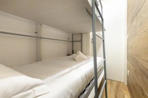 a bedroom with two bunk beds with white sheets at Hostdomus - Valle Studio in Grange Sises