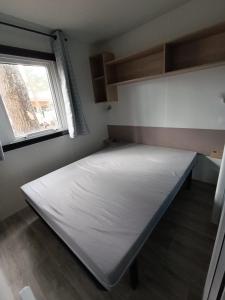 a bed in a small room with a window at Mobil-home neuf sous les pins, à proximité des infrastructures in Saint-Julien-en-Born
