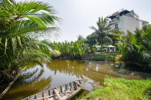 a boat on a river with palm trees and a building at Villa Ban Hien in Hiếu Nhơn