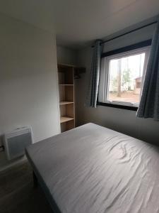 a bedroom with a bed and a window at Mobil-home neuf sous les pins, à proximité des infrastructures in Saint-Julien-en-Born
