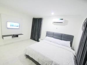 MagodoにあるKaypoint Homesの白いベッドルーム(ベッド1台、テレビ付)