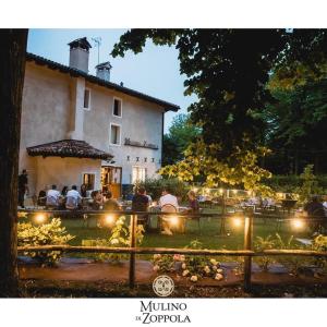 a group of people sitting at a table in front of a building at Mulino di Zoppola in Zoppola