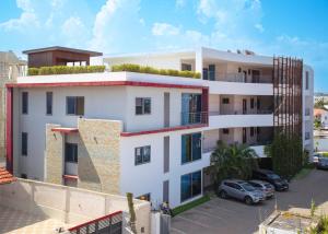 a white apartment building with a green roof at Legacy Square by QUAO REALTY in East Legon