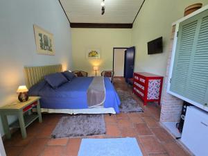 a bedroom with a bed and a table and a tv at Pousada Quintal das Hortênsias in Salesópolis +7 photos