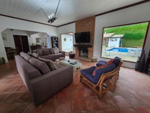 a living room with two couches and a tv at Pousada Quintal das Hortênsias in Salesópolis
