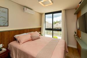 ein Schlafzimmer mit einem rosa Bett und einem Fenster in der Unterkunft Apto Moderno e Confortável no Coração de Canela in Canela