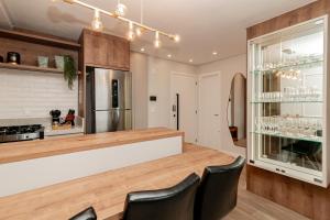 eine Küche mit einer Bar mit schwarzen Stühlen in der Unterkunft Apto Moderno e Confortável no Coração de Canela in Canela