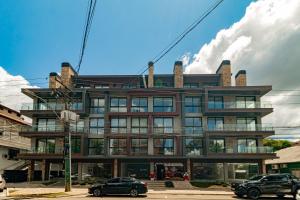 ein Gebäude mit davor geparkten Autos in der Unterkunft Apto Moderno e Confortável no Coração de Canela in Canela