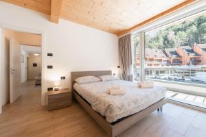 a bedroom with a bed and a large window at Appartamento Jubilant in Comano