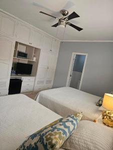 a bedroom with two beds and a ceiling fan at Jardín de la Nonna #1 in San Pedro Sula