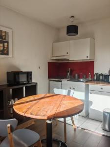 a kitchen with a wooden table and chairs in it at Charmant studio meublé avec jardinet - 25 m2 - Orsay - Le Guichet in Orsay