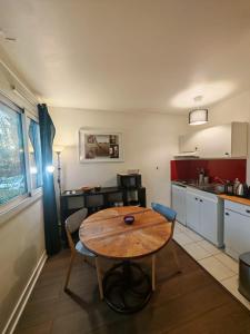 a kitchen with a wooden table in the middle at Charmant studio meublé avec jardinet - 25 m2 - Orsay - Le Guichet in Orsay