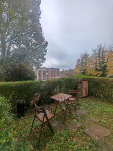 a picnic table and two chairs in a garden at Charmant studio meublé avec jardinet - 25 m2 - Orsay - Le Guichet in Orsay