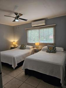 a bedroom with two beds and a ceiling fan at Jardín de la Nonna #1 in San Pedro Sula