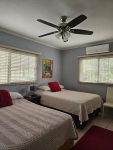 a bedroom with two beds and a ceiling fan at Jardín de la Nonna #1 in San Pedro Sula