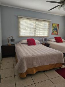 a bedroom with two beds with red pillows on them at Jardín de la Nonna #1 in San Pedro Sula +7 photos