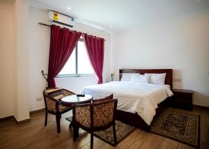 a bedroom with a bed and a table and a window at Legacy Square by QUAO REALTY in East Legon