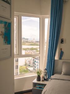 a bedroom with a window with a view of a city at 2BR Luxury riverview - Melody of the Sea Monarchy in Da Nang +16 photos