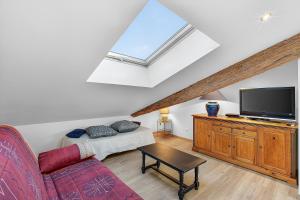 a living room with a couch and a flat screen tv at Gîte Uncinatum - La Grange Du Logis in Villevieille