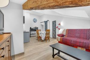 a living room with a red couch and a table at Gîte Uncinatum - La Grange Du Logis in Villevieille