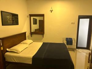 a bedroom with a bed and a mirror in it at Thomasz Lodge 2 in Kandy