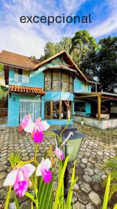a blue house with pink flowers in front of it at Casa na Montanha em Monte Verde in Monte Verde