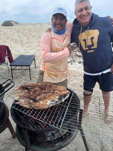 a man and a woman standing next to a grill at Avistamiento de Ballenas y Campamento Todo incluido!! Mínimo 3 noches en Mag Bay in Punta Cove